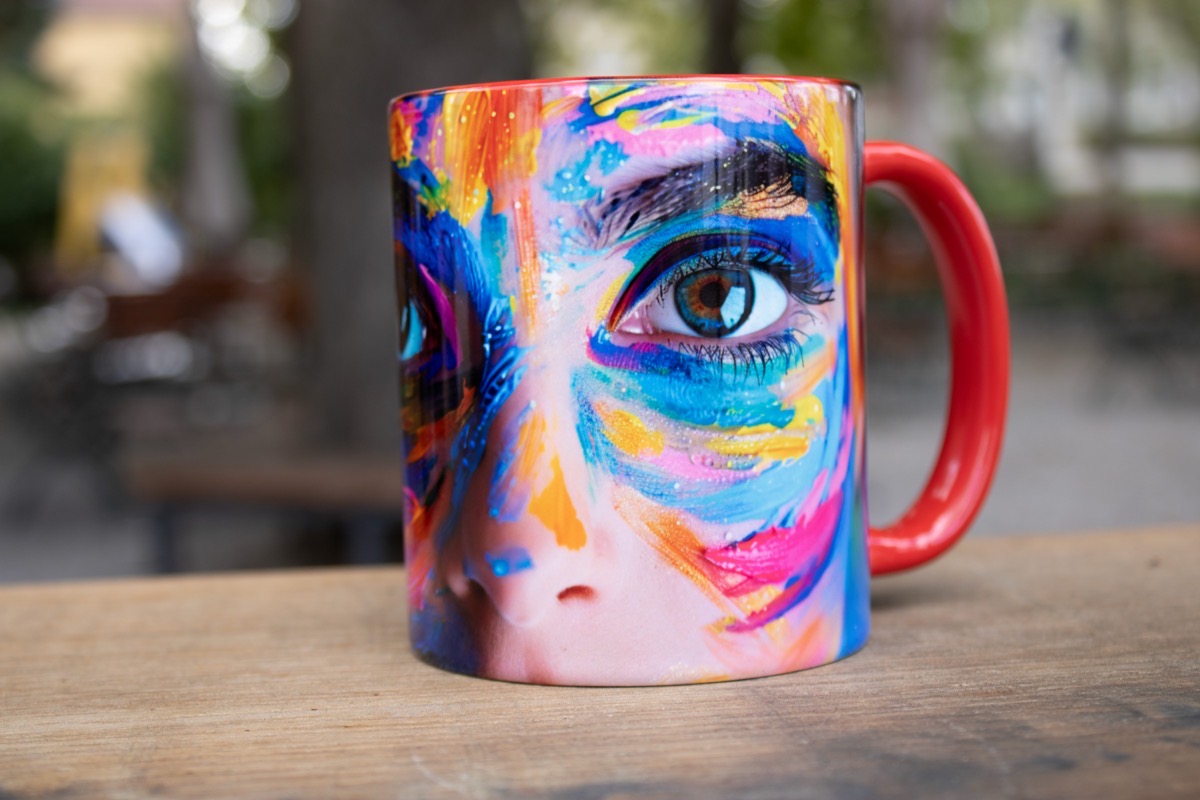Vollflächig bedruckte Tasse mit farbigem Gesichtsmotiv und rotem Henkel